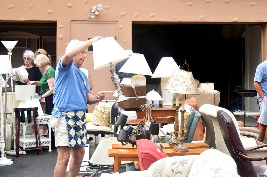 Tom Vitro moves lamps around while volunteering at the sale.