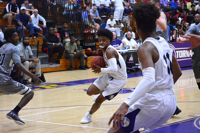 Jaylen Jones splits two defenders and heads toward the basket.