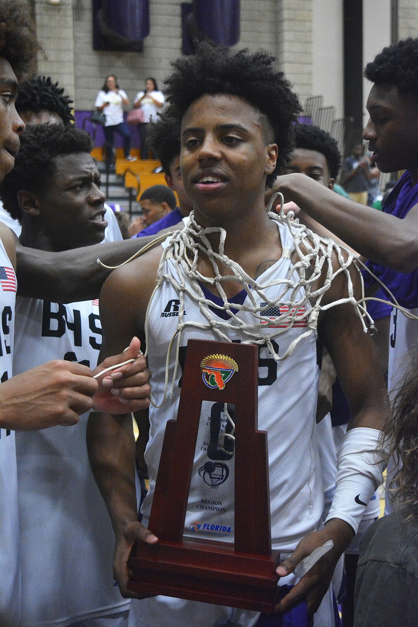 Jaylen Jones gets the net hung around his neck, regional trophy in hand, following his game-winning layup.