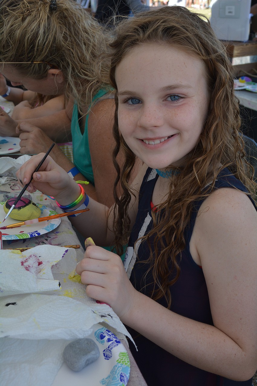Nine-year-old Mia Hynes, of Sarasota, paints a peace sign on a rock at the Sarasota Rocks booth.