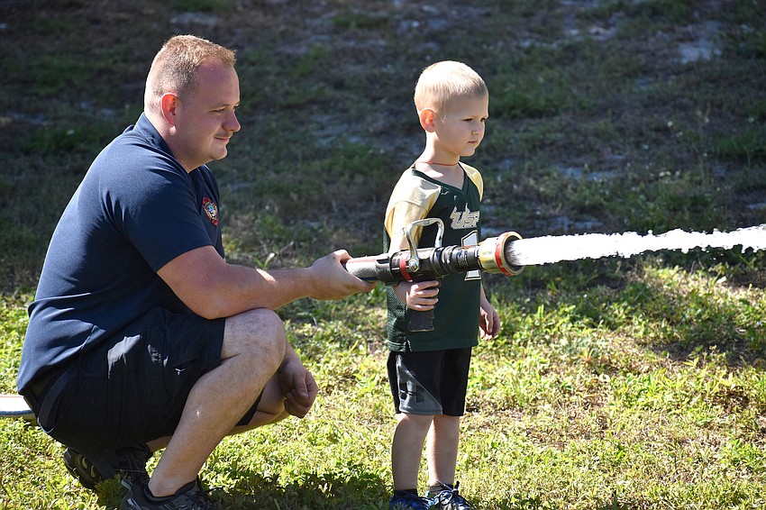 Chase Bullock, a firefighter, helps Colton Adams test out a fire house.