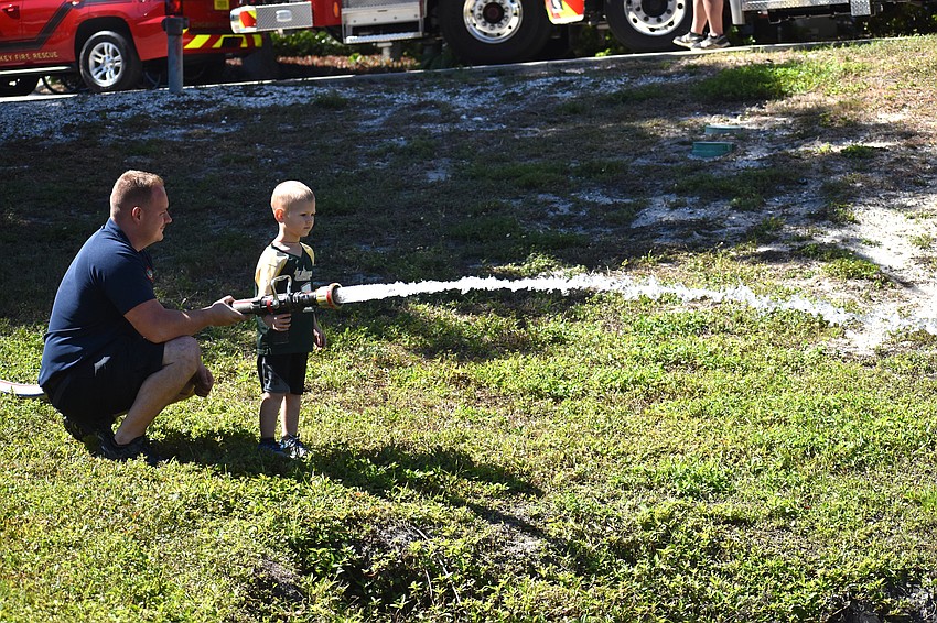 Chase Bullock, a firefighter, helps Colton Adams test out a fire house.