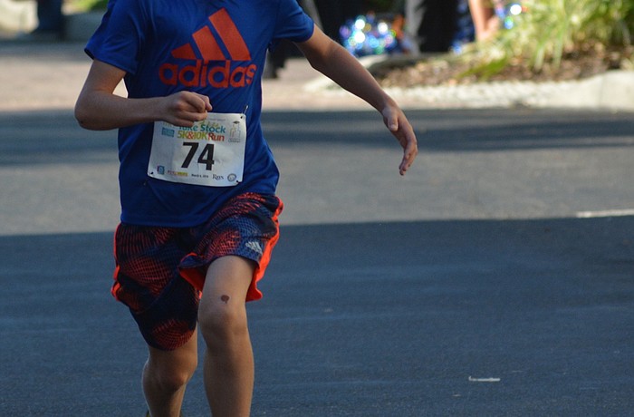 Summerfield's Jonathan Leatt, an 11-year-old McNeal student, soars above the ground as he wins the overall 5K race in 18:28.