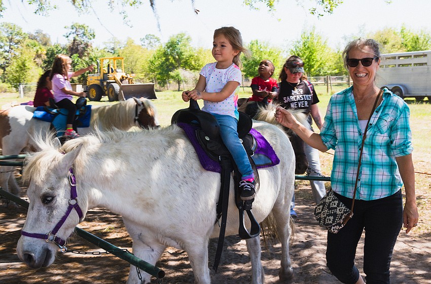 Lori Miller assists Aria Miller on her pony, Feisty.