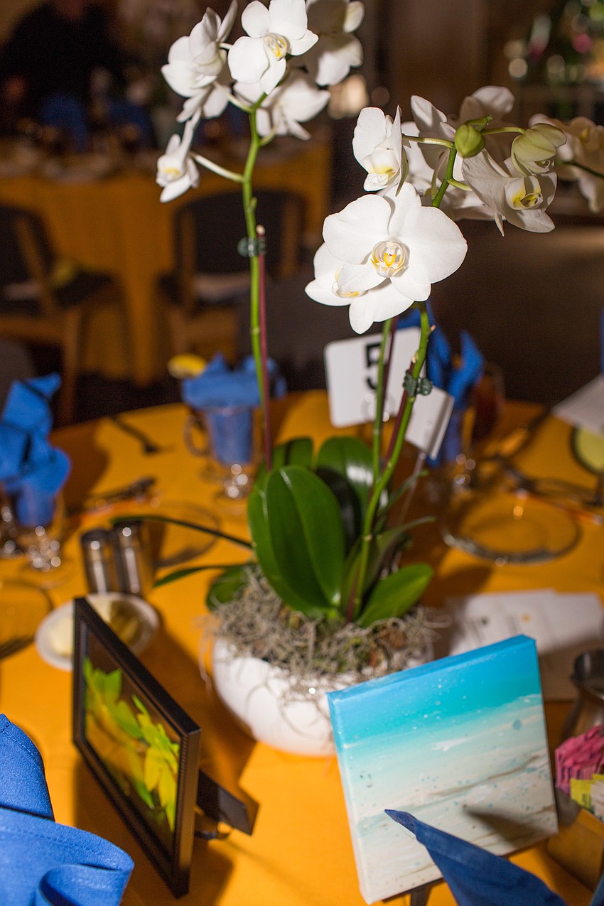 Orchids, along with paintings and photographs made by the students, centered the tables.