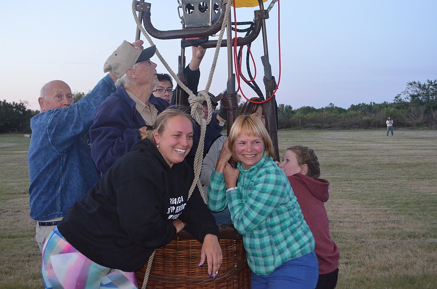 Sisters Yulia Skurikhina, from Miami, and Natalia Skurikhina, visiting from Russia, hold down a balloon with others waiting for a ride.