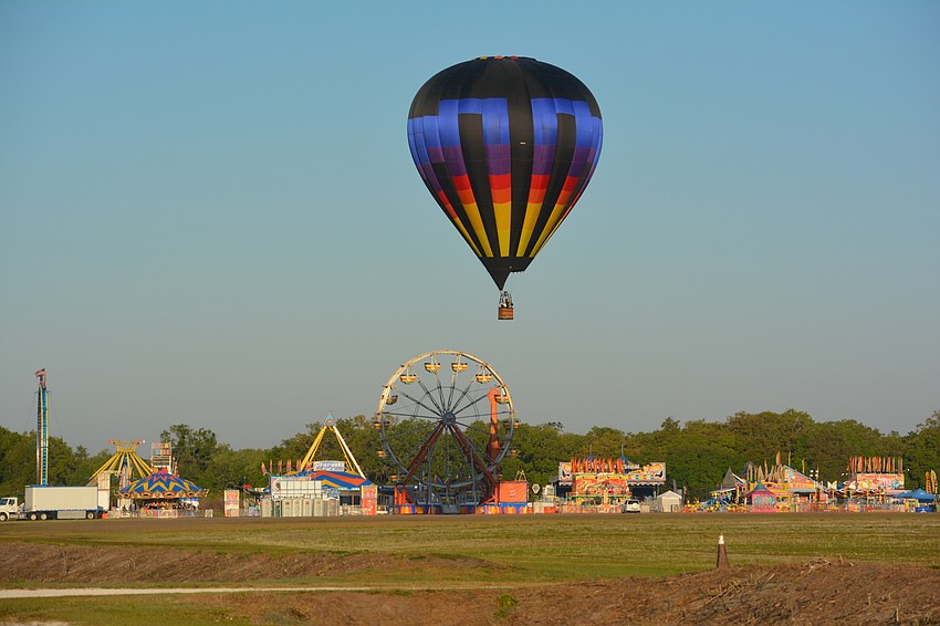 A hot air balloon gets ready to touch down next to the carnival rides at the Sarasota Balloon Festival.