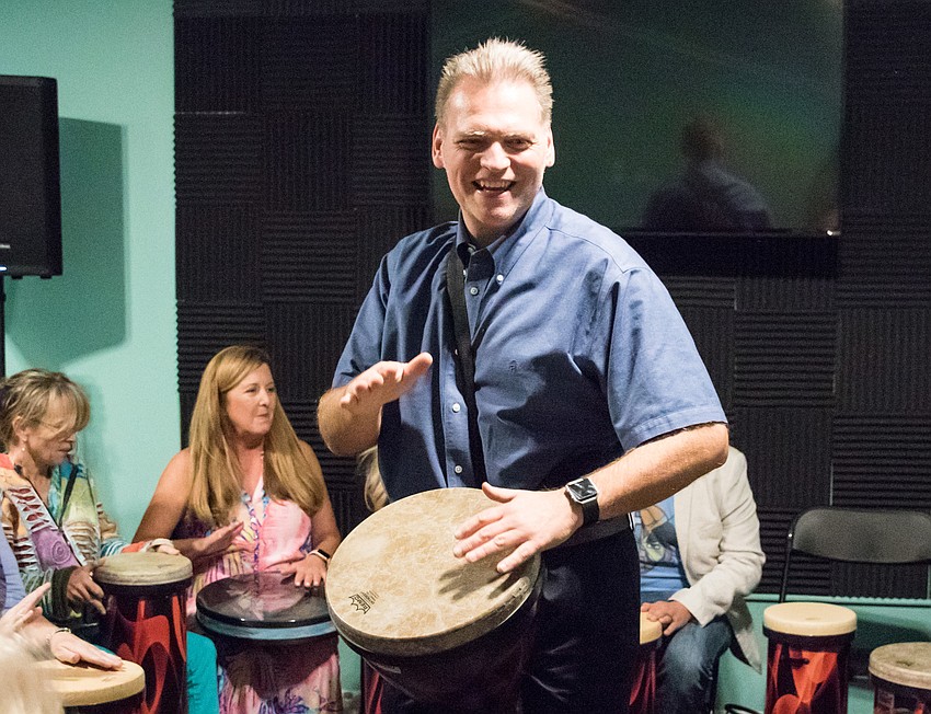 Erik Dunton leads a group drumming session during Positive Repercussions' grand opening.