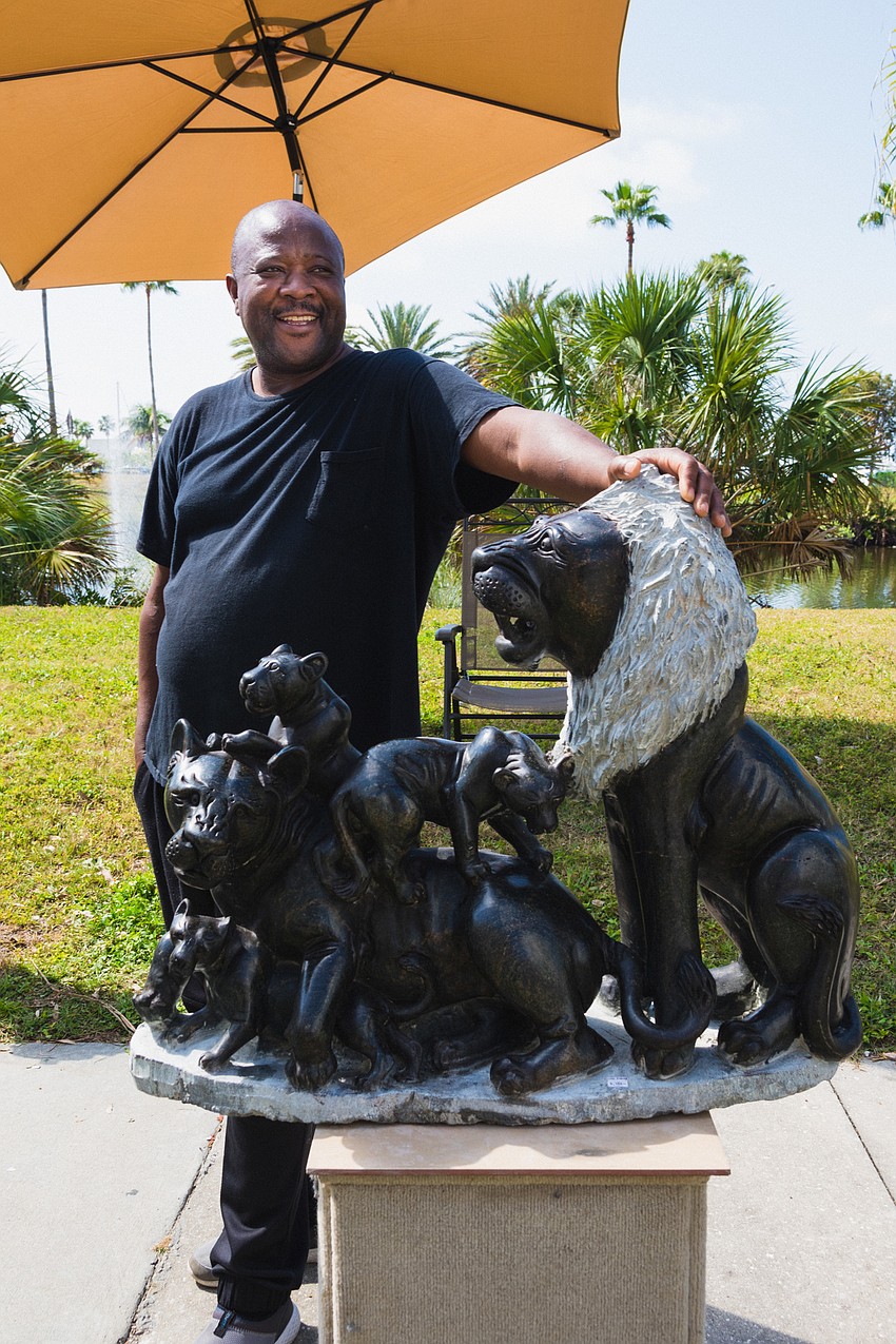 Peter Rujuwa stands next to one of his stone sculptures.
