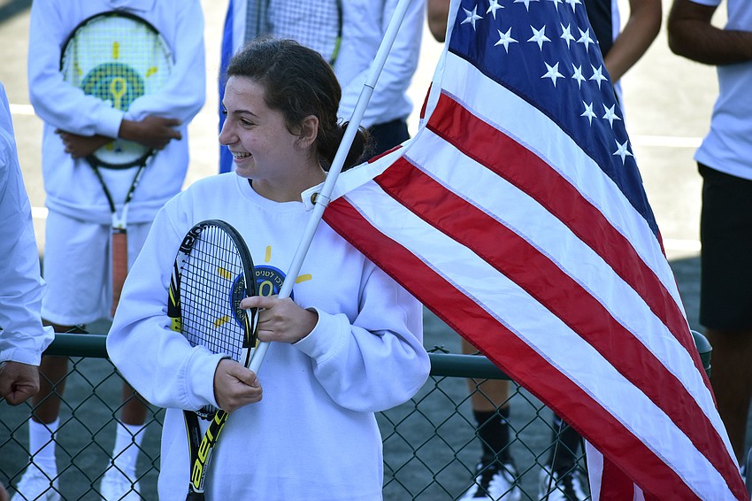Athlete Jessica Bekkerman holds the American flag as Yoni Yair introduces her.