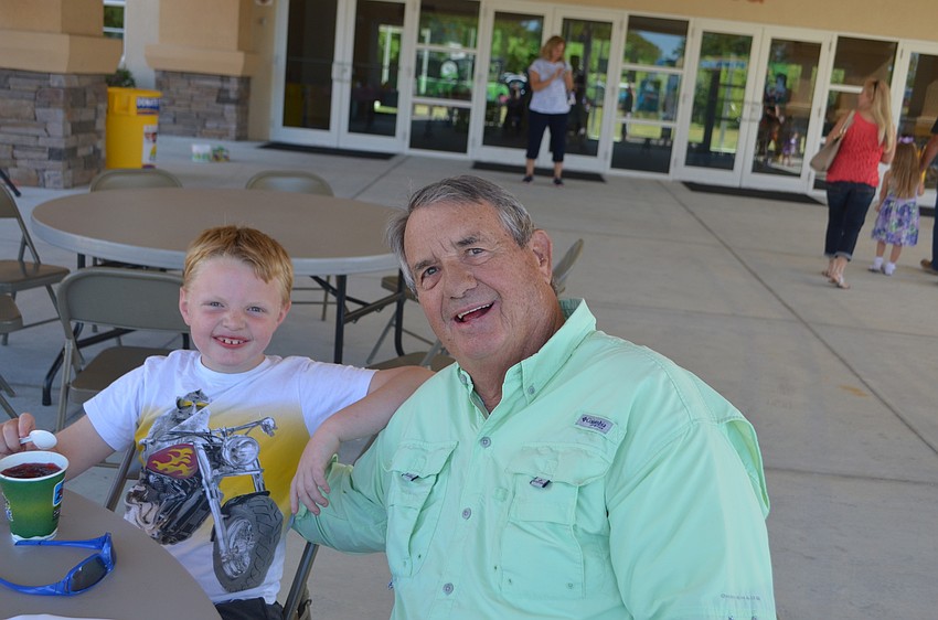 Mitchell Shaefer, 6, and his grandfather, Jon Eckert, of River Club, eat snow cones under the pavilion while they wait for the egg hunt to start.