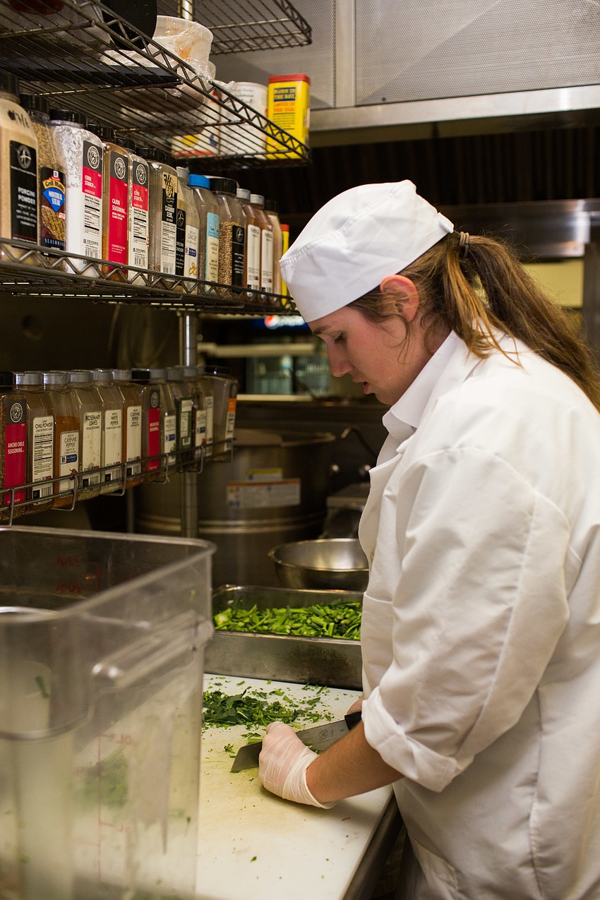 USF student Jocelyn Riley chops broccoli stems.
