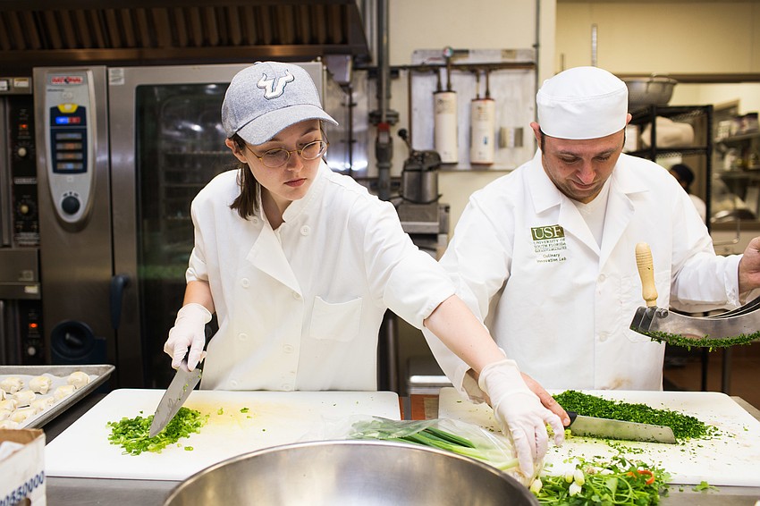 USF students Connor Flick and Patrick McGeorge chop scallions.