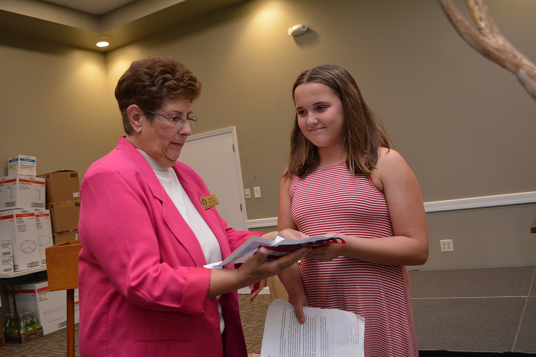 Elks essay chairwoman Kathy Dattilo hands an American flag, certificate and gift card to Freedom Elementary School&#39;s Ashley Black, who won first in the fourth-fifth grade division.