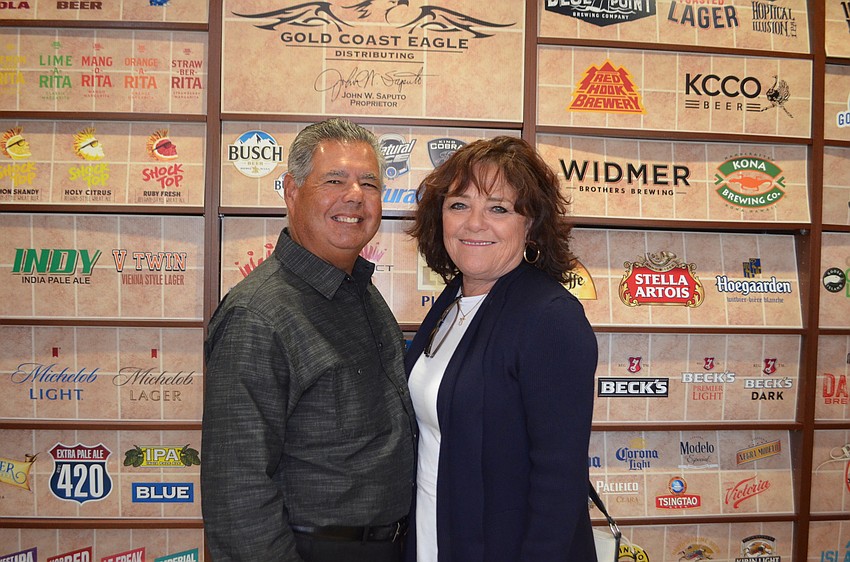 Michael and Susan Demeo stand in front of a large wall denoting all the alcohol served at Gold Coast Eagle Distributing. They drove all the way from Venice to see the show.