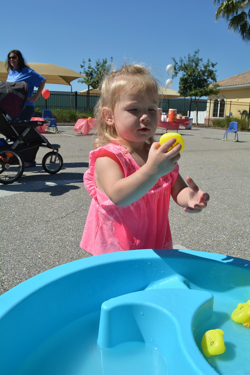 Two-year-old Payton Williams hunts through the rubber ducks with the help of her mom, Kiddie Academy teacher Brooke Williams.