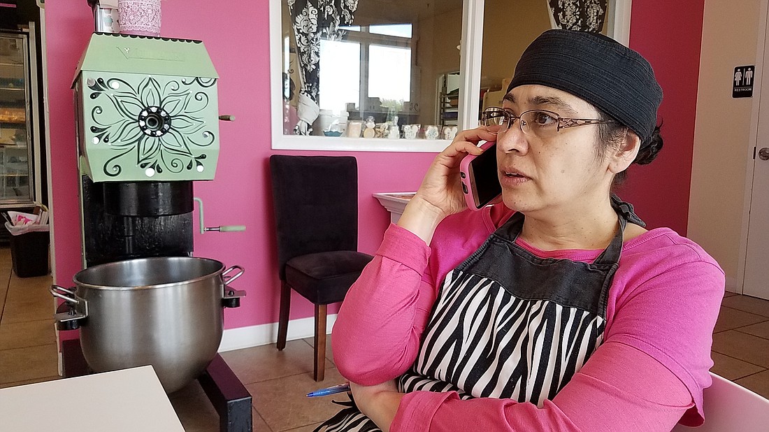 Pastries by Design owner Alejandra Hernandez fields a call about damage to her building. She says her back has been hurting since the incident.