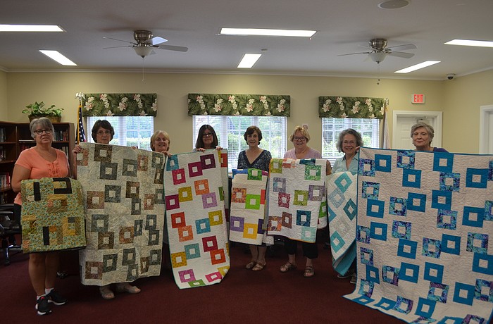 Beth Stub, Betsy Hinkley, Jane Benace, Joanne Bouda, Jean Driver, Lynne Sheal, Mary Jane Diaz and Donna Guess share a laugh as they hold up the blankets they made for the Florida Cancer Specialist hospital.