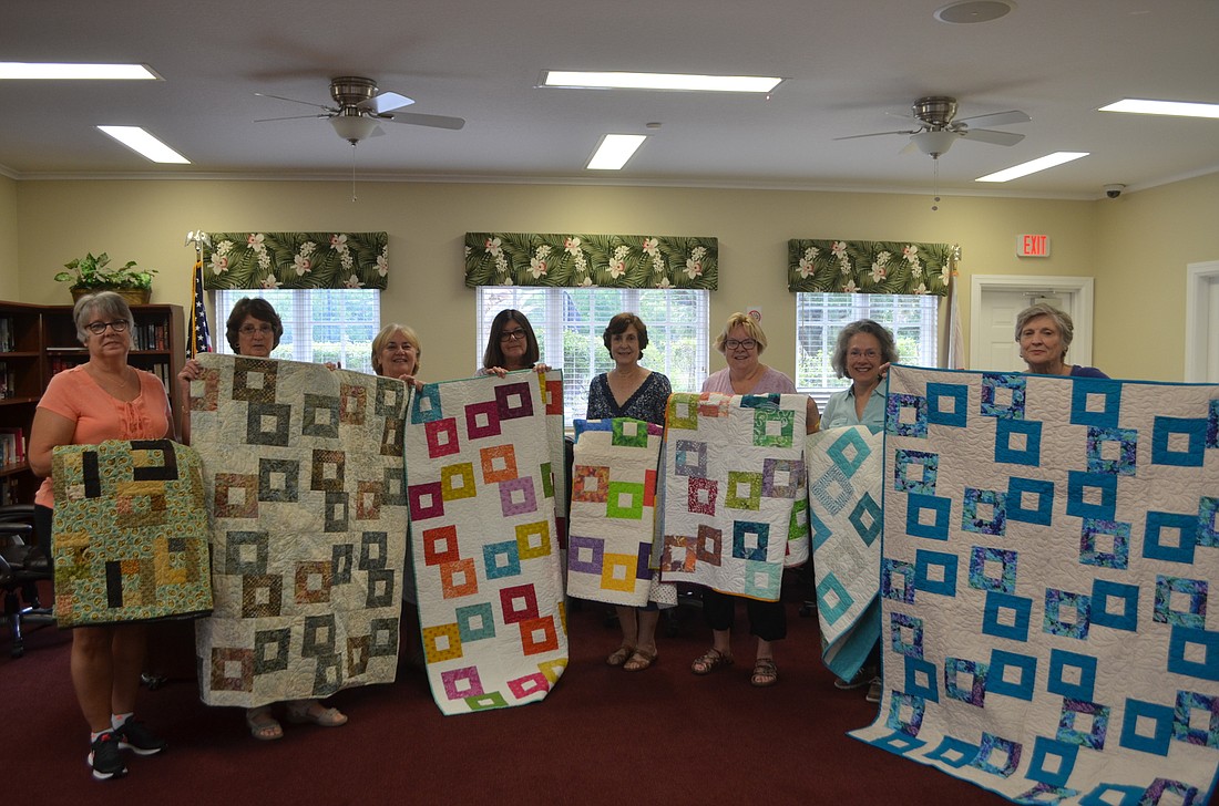 Beth Stub, Betsy Hinkley, Jane Benace, Joanne Bouda, Jean Driver, Lynne Sheal, Mary Jane Diaz and Donna Guess share a laugh as they hold up the blankets they made for the Florida Cancer Specialist hospital.
