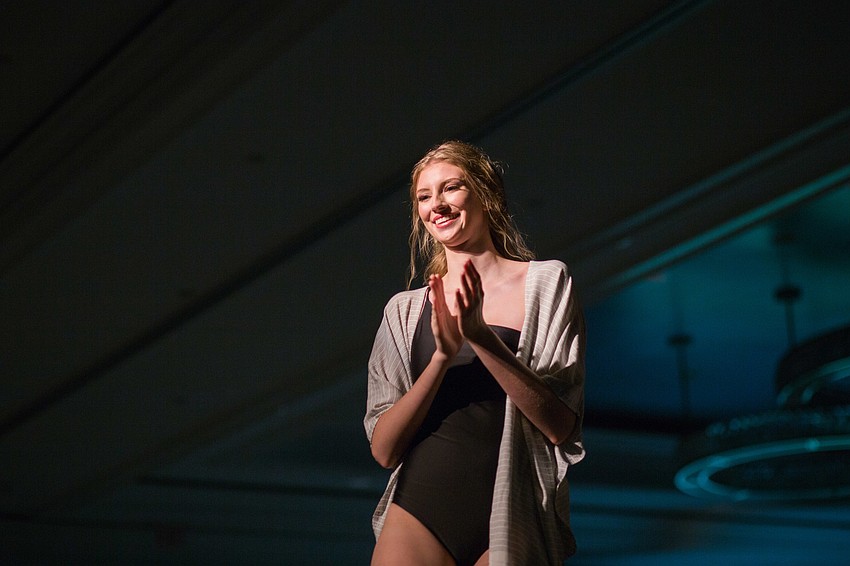 A model claps and smiles as she makes her final lap around the stage.