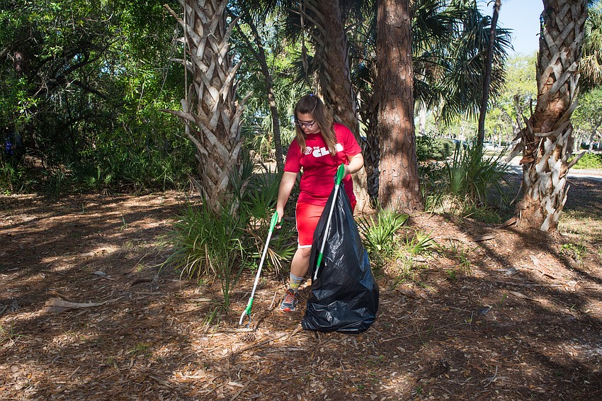 Boys and Girls Club member Delaney picks up litter at Potter Park.