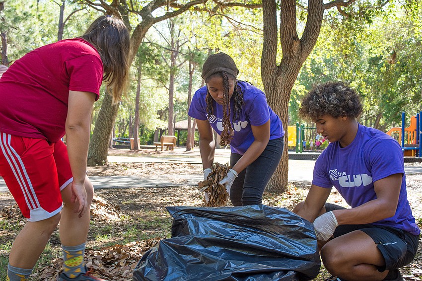 Delaney, Aysha and Angelo pick up leaves at Potter Park.