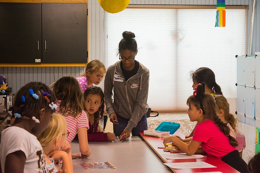 Sydney of the Boys and Girls Club helps pass out activities materials for Girls Inc. students.