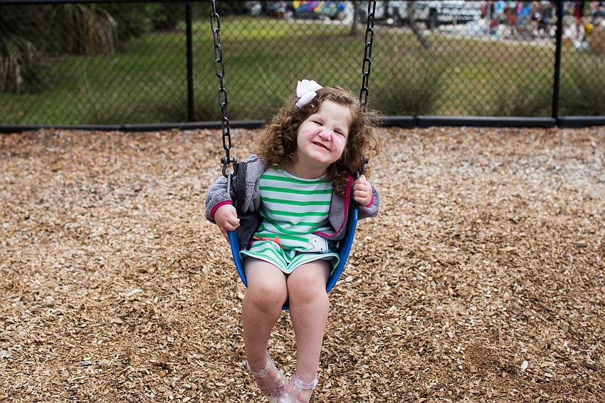 Braelyn Lengacher smiles for the camera as she swings.