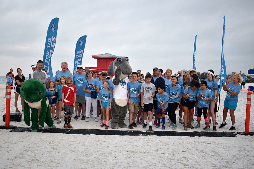 Participants in the 1-mile fun-run/walk pose for a photo with Shelley the Sea Turtle and Gilly the Shark.