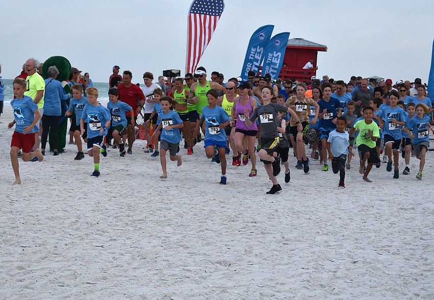 Participants in the 5K run take off from the finish line.