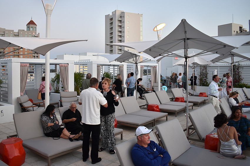 Guests grab a drink and lounge by the rooftop pool.