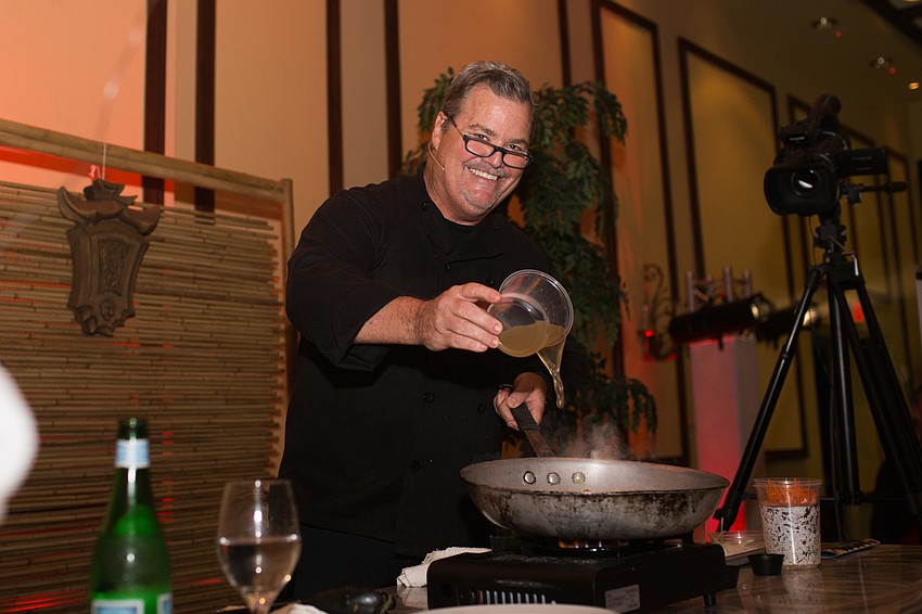 Chef Tommy Klauber pours chicken stock into his pan.