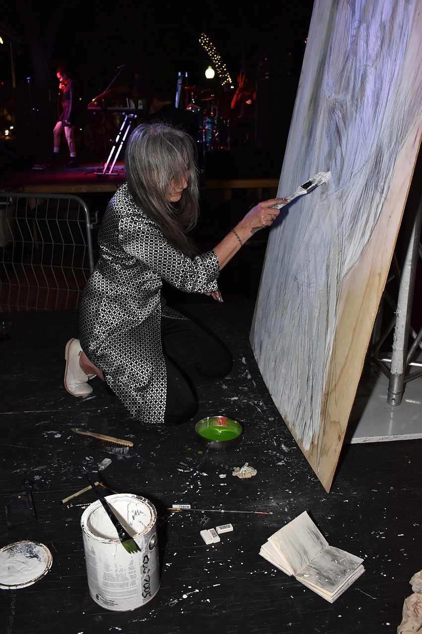 Artist Theresa Gray of Taos, New Mexico created artwork with graphite stick, eraser and house paint on plywood while bands performed.