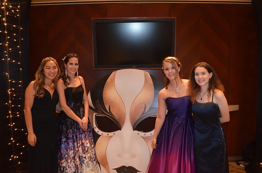 Seniors Morgan Lakomiak, Cristina Rosabal, Erika Rojas and Carley Dulin gather around a huge masked face at the prom.