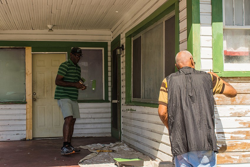 Headley Black and Jetson Grimes paint the exterior of the home.