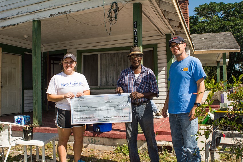 Asia Lorde and Uzi Baram present contractor Calvin Bryant, center, a check for the paint and supplies.