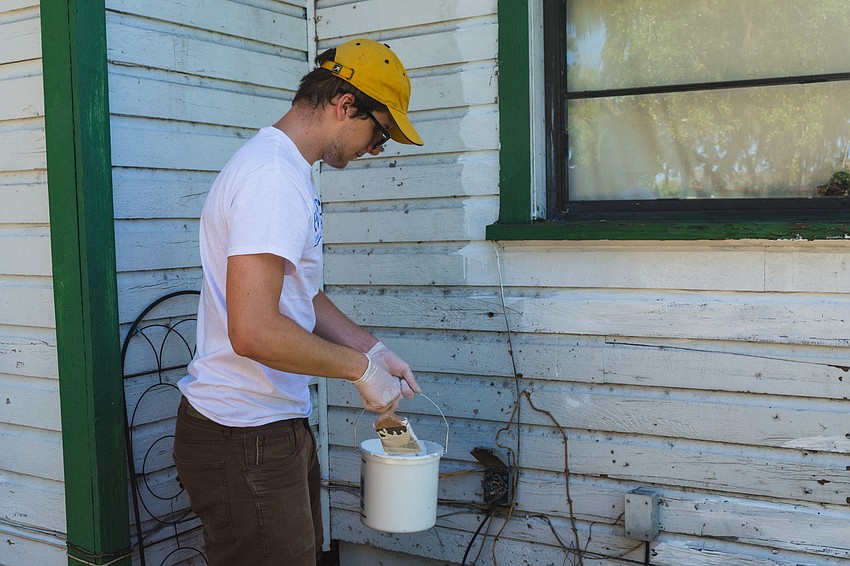 Alex Tiaterry paints the exterior of the home.