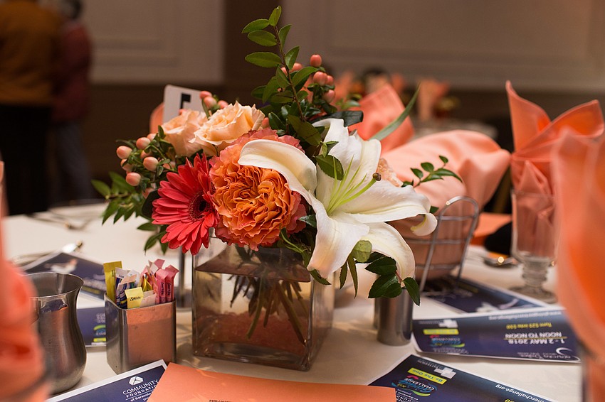 Floral arrangements and light orange napkins decorated the tables.