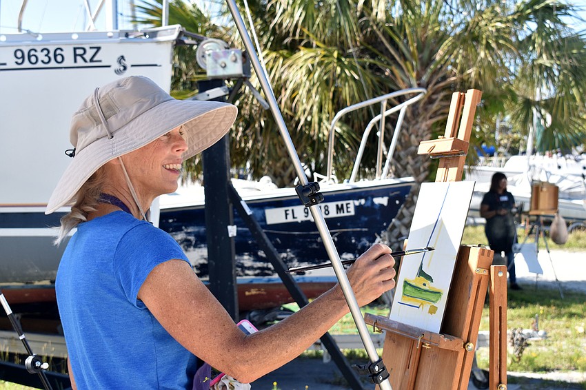Nancy Clayburn paints a green sailboat, which is housed on the Sarasota Sailing Squadron property.