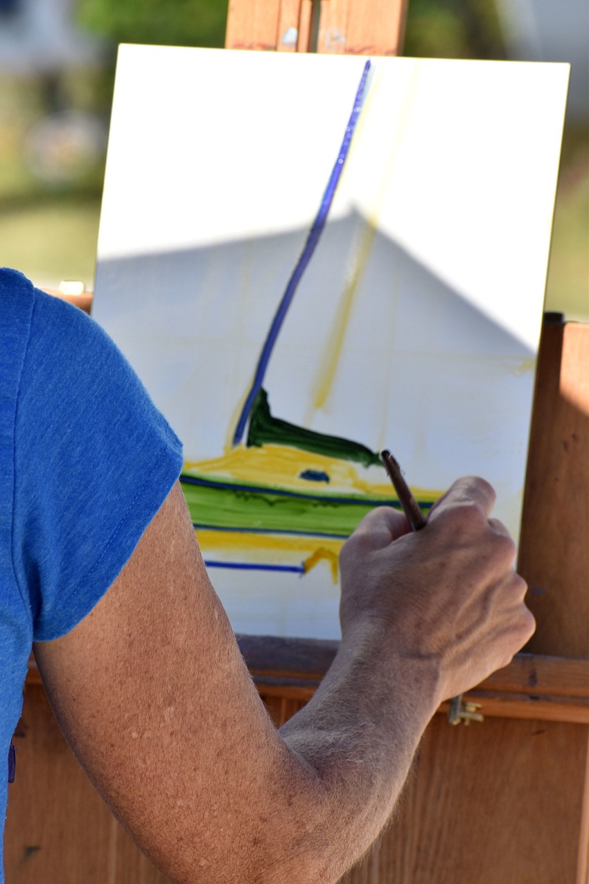Nancy Clayburn paints a green sailboat, which is housed on the Sarasota Sailing Squadron property.