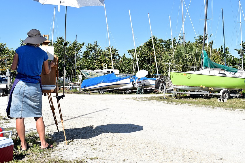 Nancy Clayburn paints a green sailboat, which is housed on the Sarasota Sailing Squadron property.