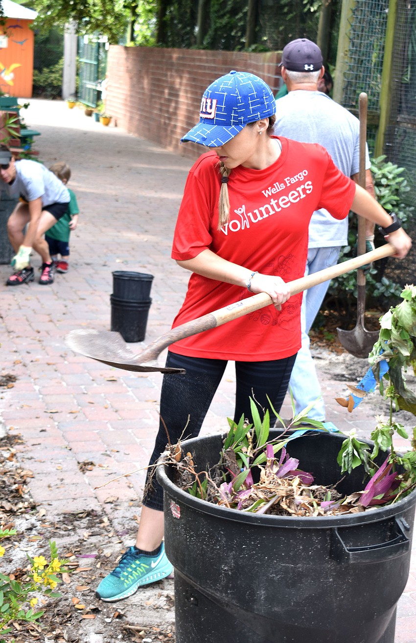 Morgan Buccolo moves leaves into a garbage can.