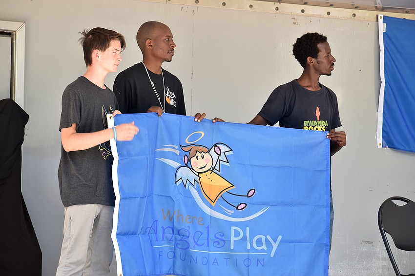 Representatives from the last playground built in Rwanda hold a flag.