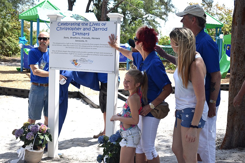 The Ditmars family reads the plague sitting in front of the playground.