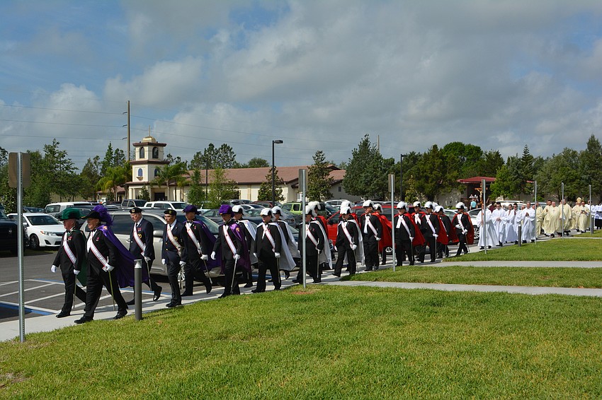 The Knights of Columbus lead clergy members from the former church building to the new church.