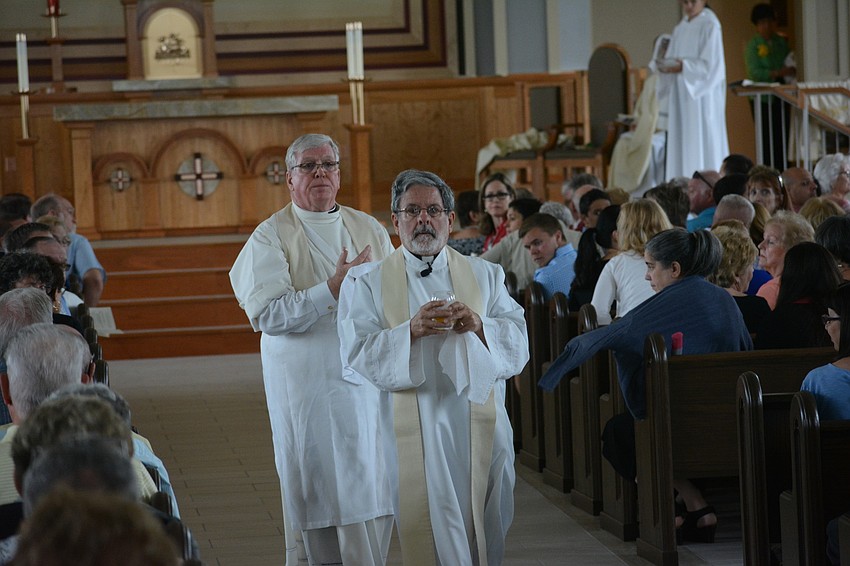 Rev. Michael Scheip leads Rev. Frank Dewane, the bishop of the Diocese of Venice, as they go about anointing the walls of the church.