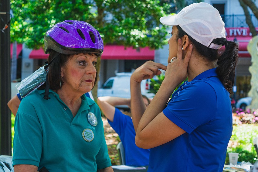 Christine Diaz shows Bonita Chambers how to properly wear a bike helmet.