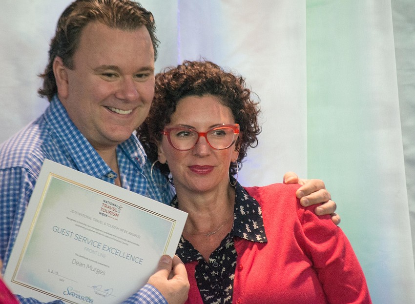 Dean Murges and Nicole Hancock accept their awards on stage.