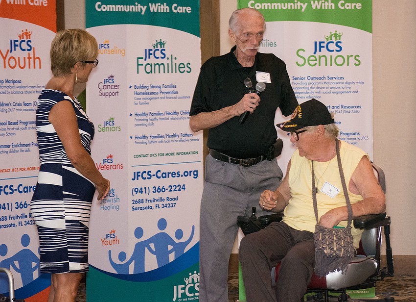 Wheels 4 Purple Hearts CEO Jack Thompson presents veteran Ed Talhurst with a customized power wheelchair.