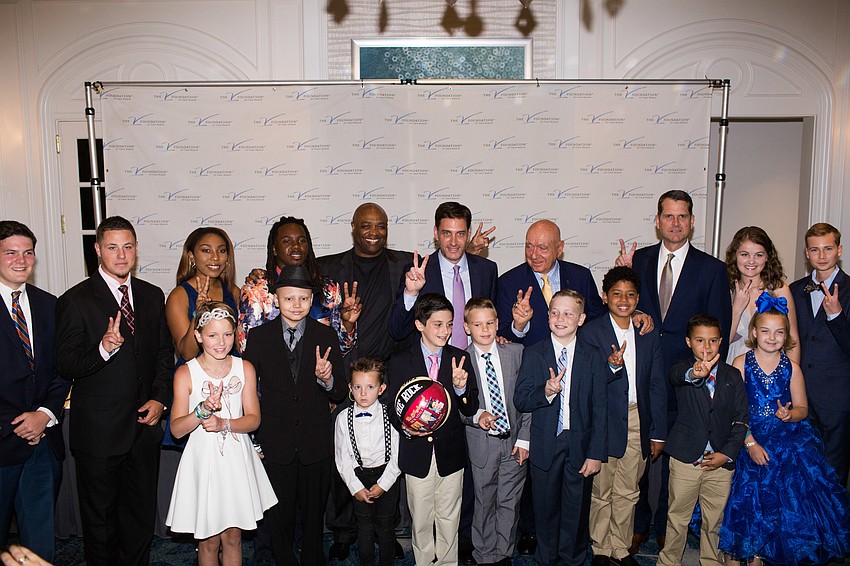 The panel speakers, children and their families gather for a photo.